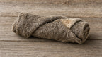 Sheep skin jerky roll side view on weathered wood